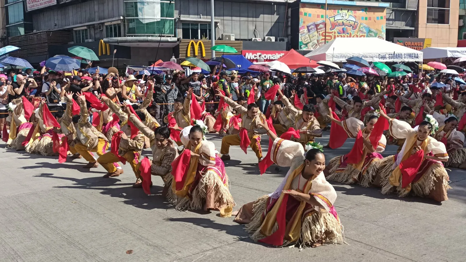Tanečníci v červených a zlatých kostýmech vystupují na ulici při Sinulogu v Cebu City