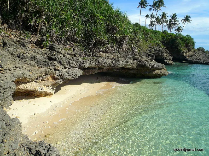 Turquoise water, palms and limestone beside a small beach on Guimaras