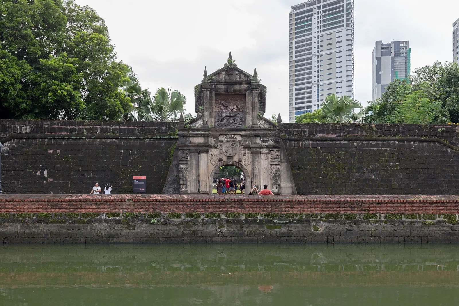 Fort Santiago entrance across a moat with modern Manila buildings behind