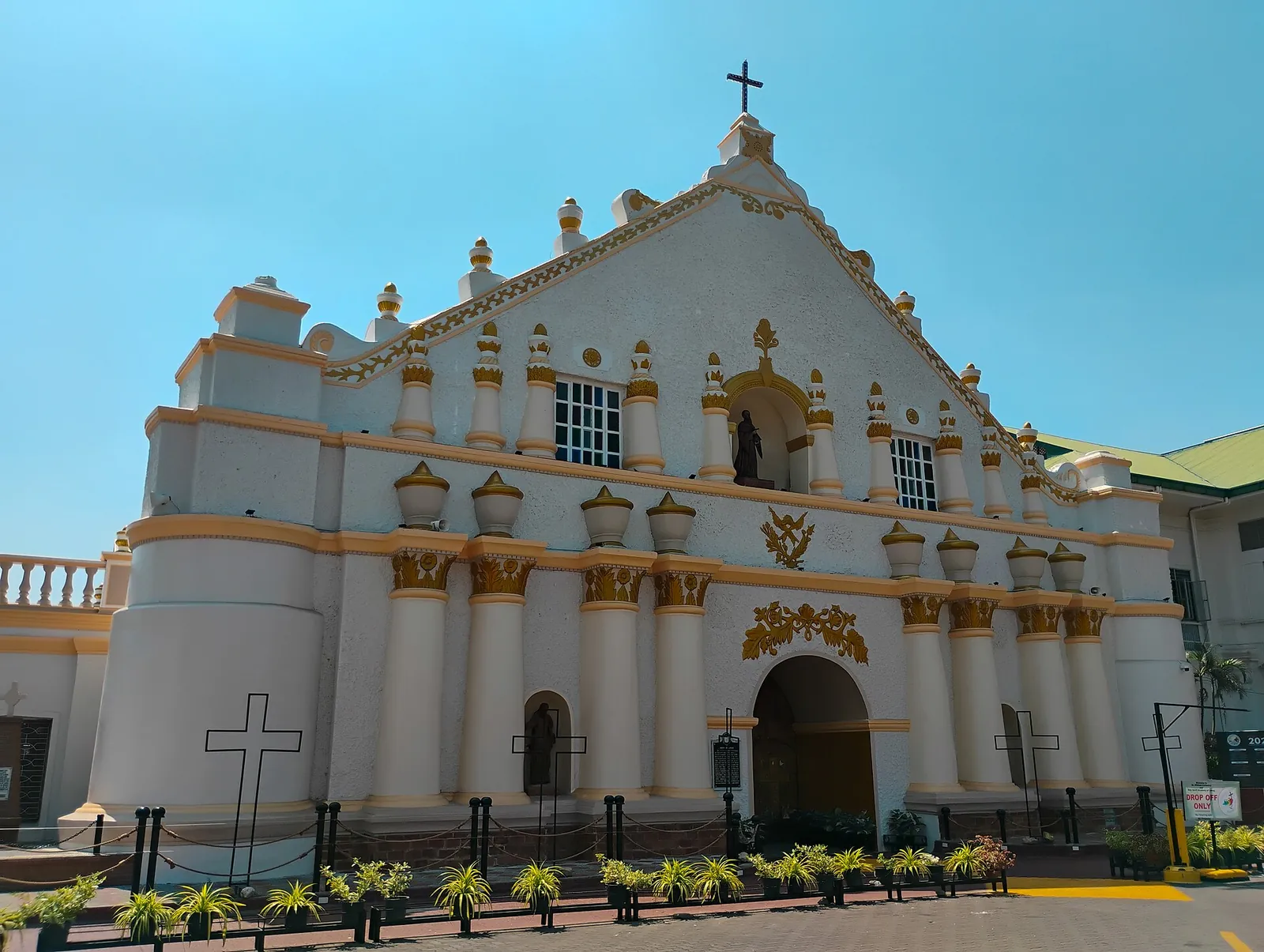White and gold facade of Laoag Cathedral beneath a blue sky