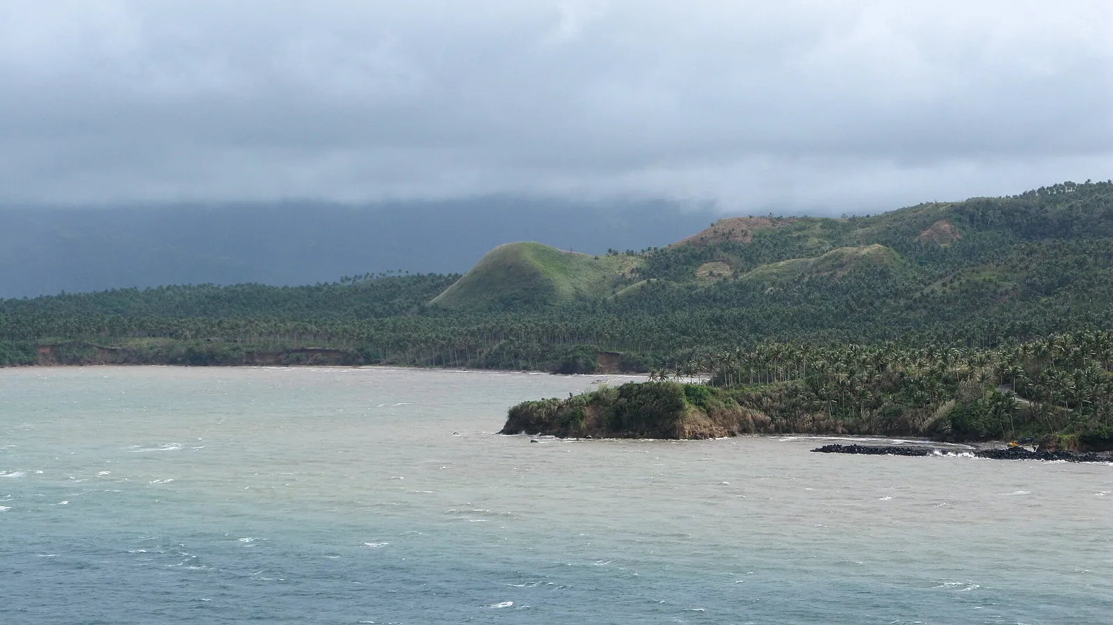 Legazpi Bay and wooded headlands under a cloudy sky
