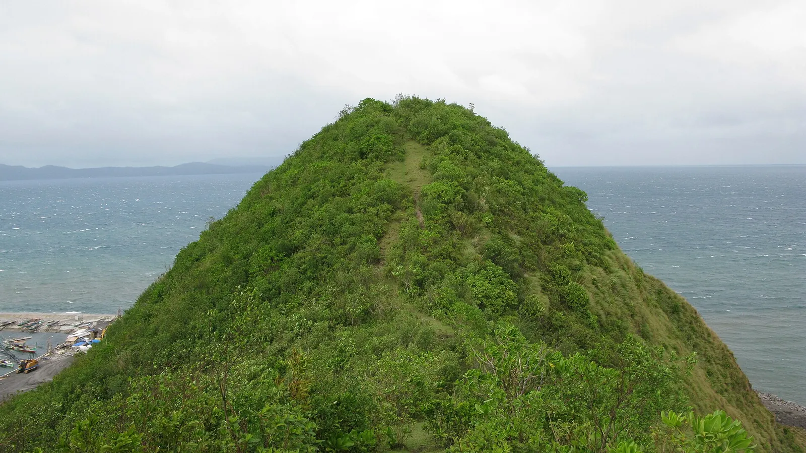 Green coastal hill above blue water at Legazpi