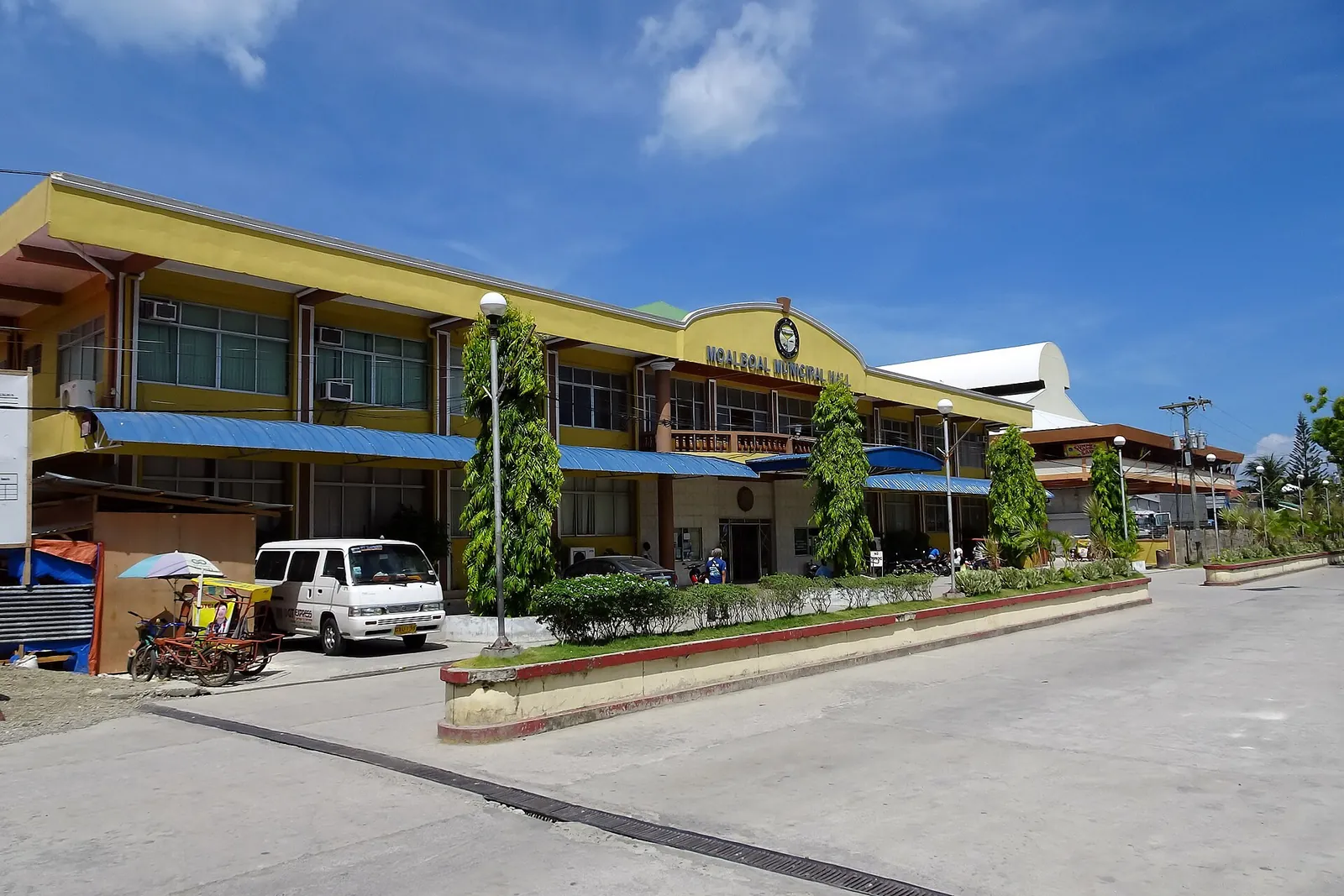 Yellow town building and tricycles beside a sunlit road in Moalboal