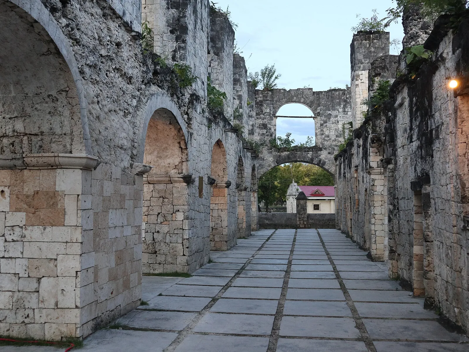 Stone walls and arches lining an open corridor inside Oslob’s Cuartel ruins