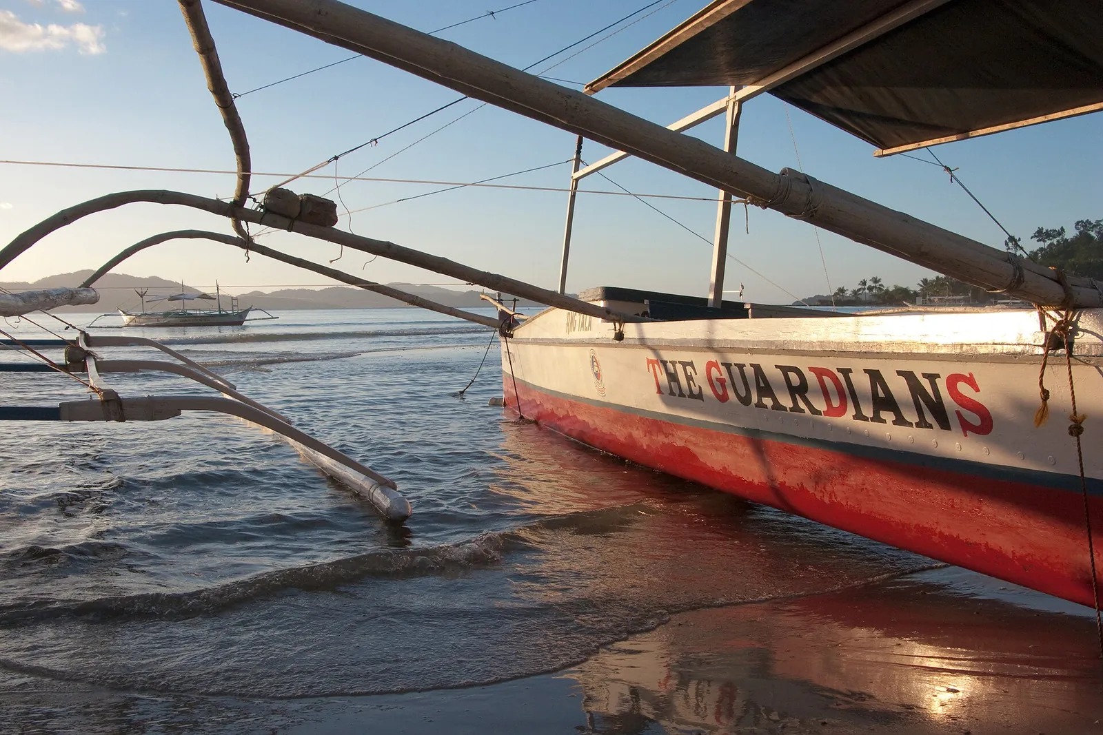 Wooden outrigger beams and a banca boat resting in shallow water at Port Barton