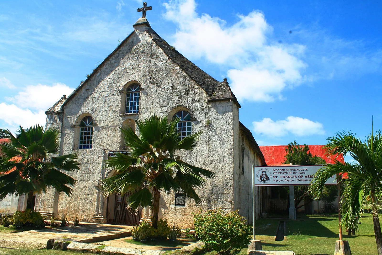 Stone facade and red roof of Saint Francis of Assisi Church under a blue sky