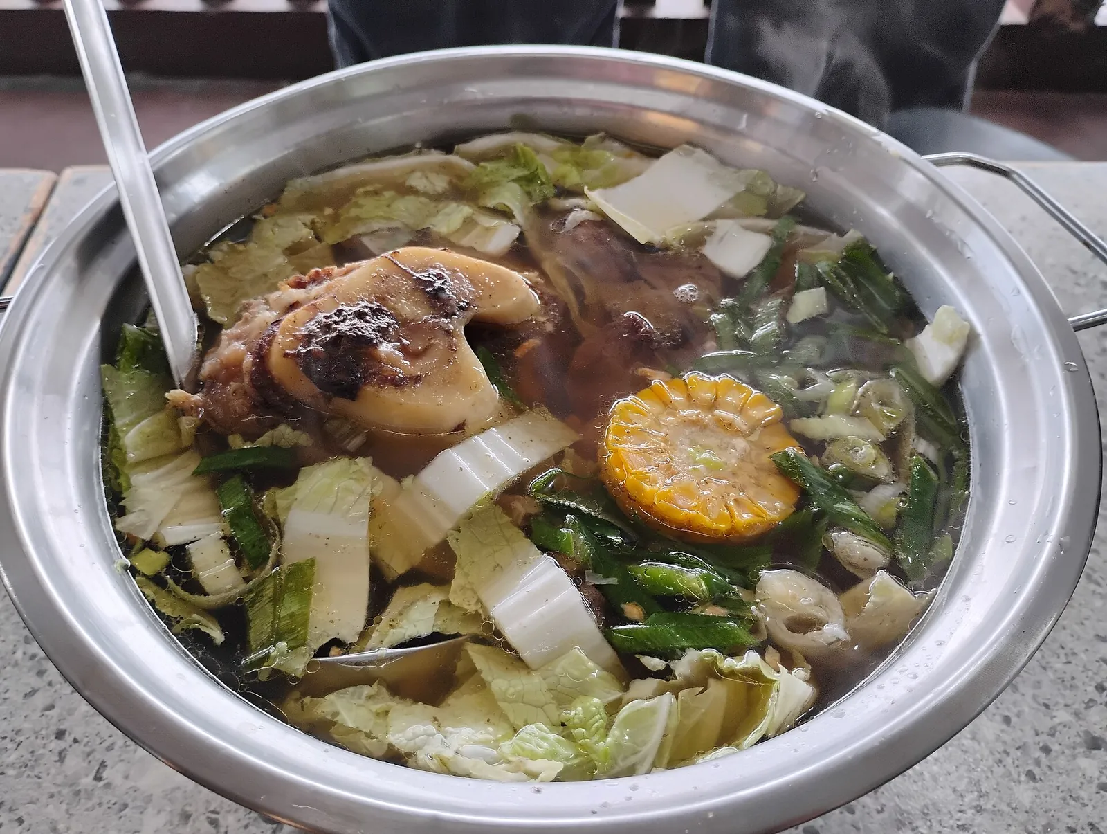 Bulalo soup with beef shank, corn and vegetables in a metal bowl