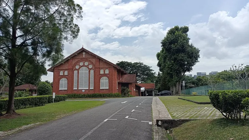 St Georges Church i røde mursten ved træer og en rolig vej i Singapore