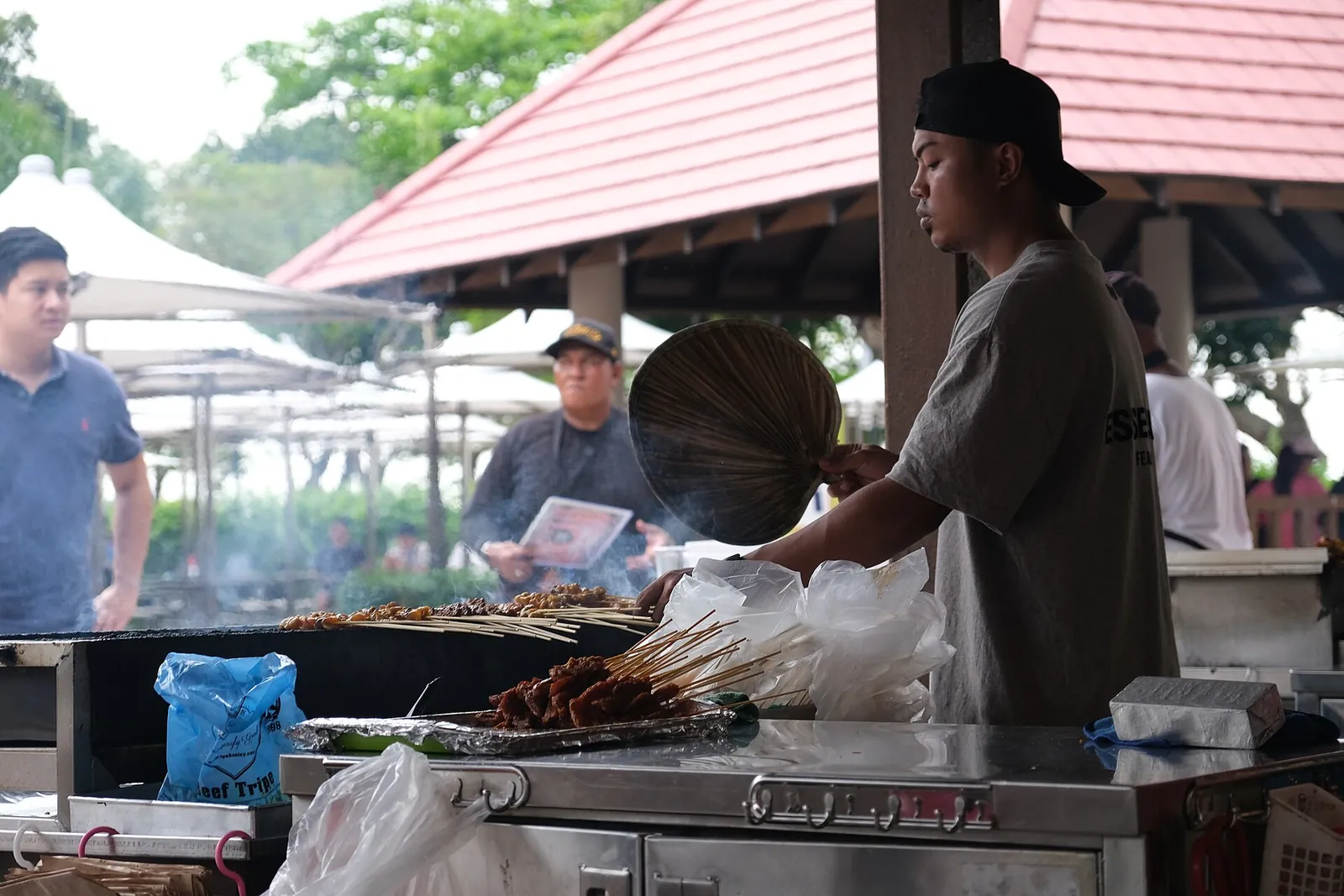 Ein Hawker grillt Satay im East Coast Lagoon Food Village