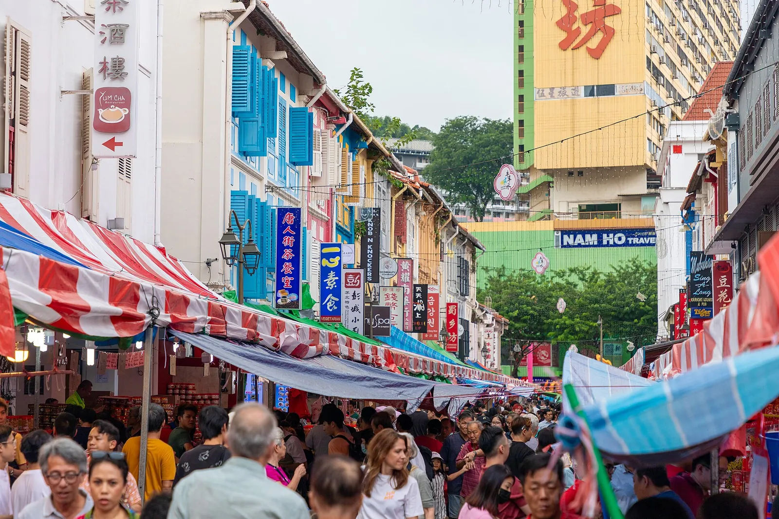 Tłumy robiące zakupy pod pasiastymi markizami na targu ulicznym Chińskiego Nowego Roku w singapurskim Chinatown