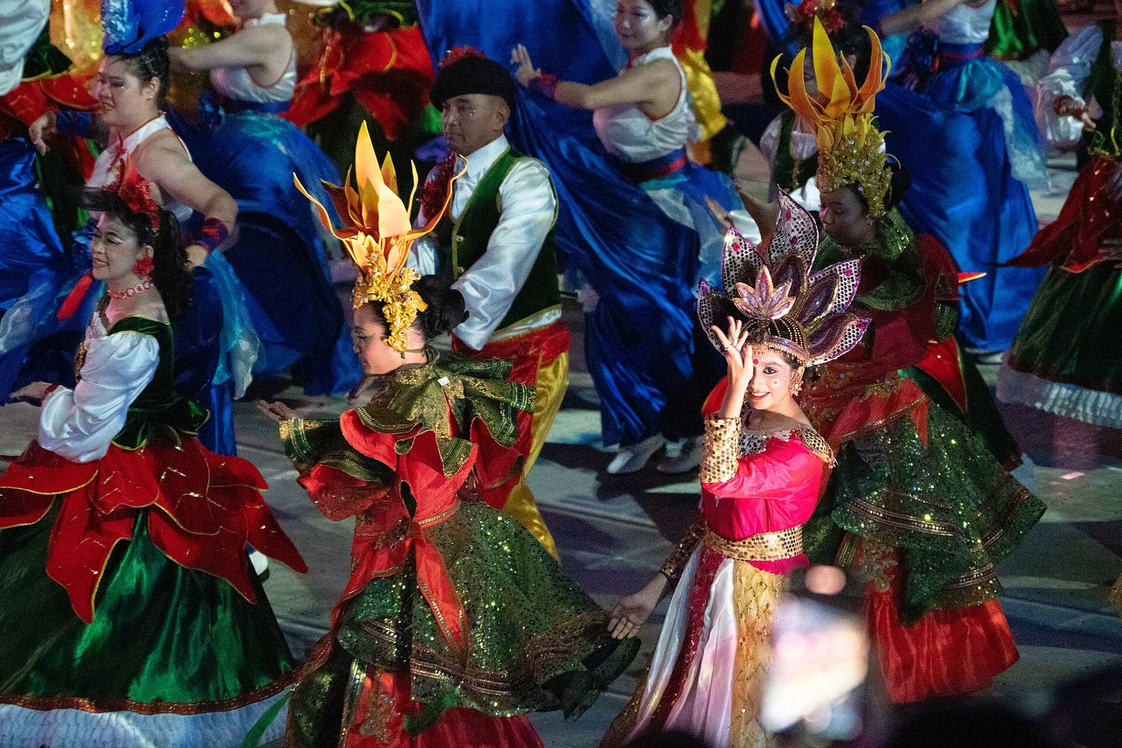 Artyści w jaskrawoczerwonych, zielonych i niebieskich strojach tańczący podczas Chingay Parade w Singapurze