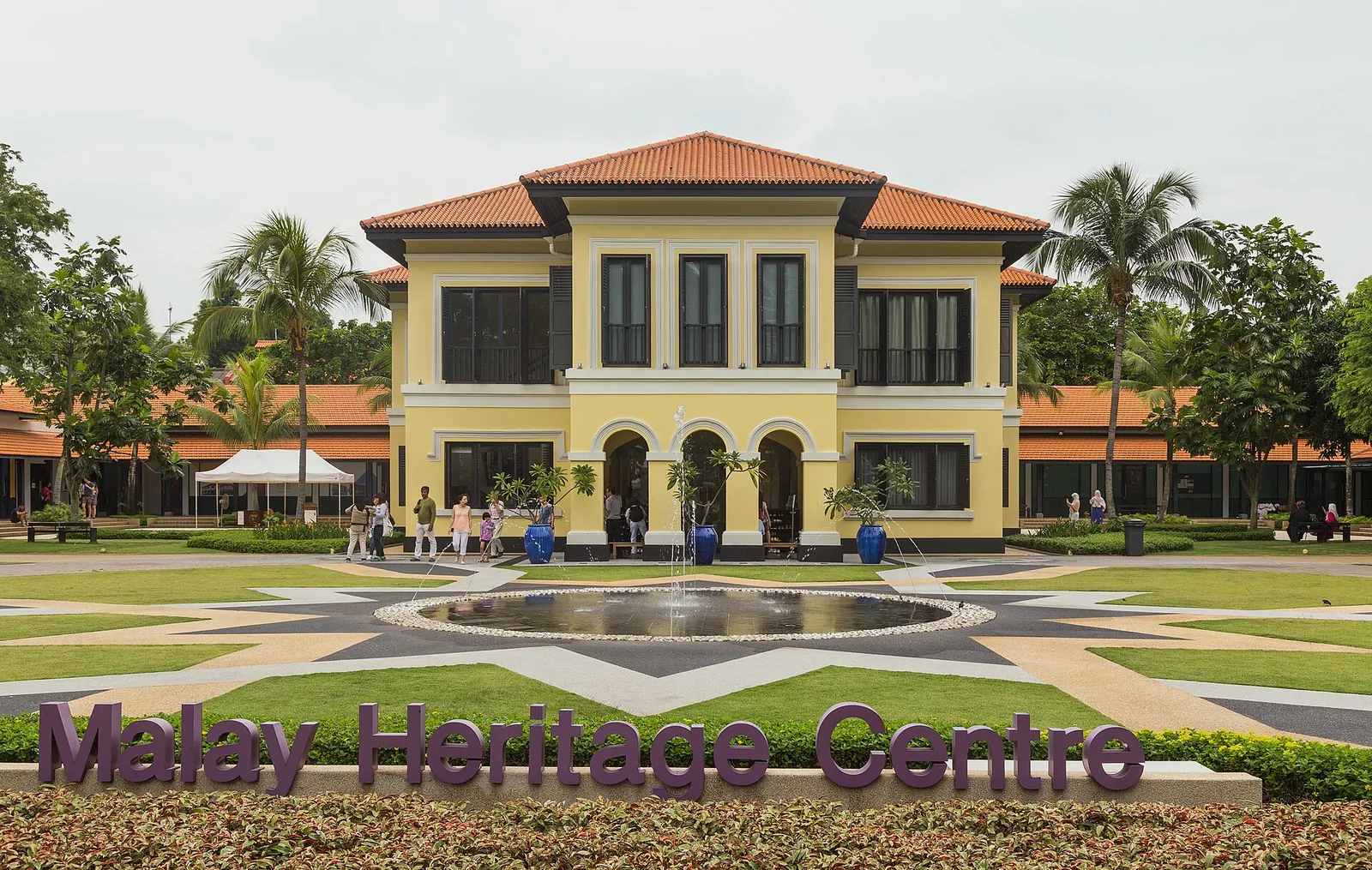 Gelbes früheres Kampong-Glam-Palastgebäude hinter einer Rasenfläche in Singapur