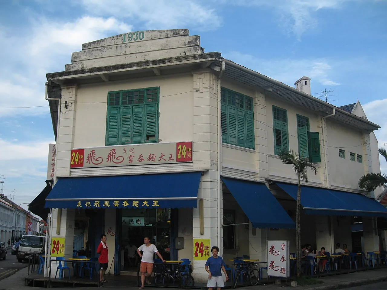 Hjørneshophouse med grønne skodder og blå markise ved Joo Chiat Place i Singapore