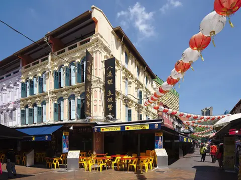 Sluncem zalité domy s obchody Chinatown pod červenými lampiony a modrou oblohou