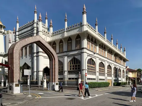 White side façade and pointed towers of Sultan Mosque against a blue sky
