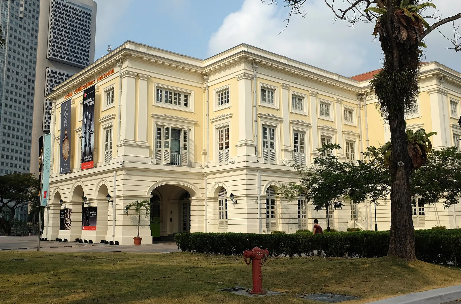 Krémová budova Asian Civilisations Museum vedle trávníku a stromu