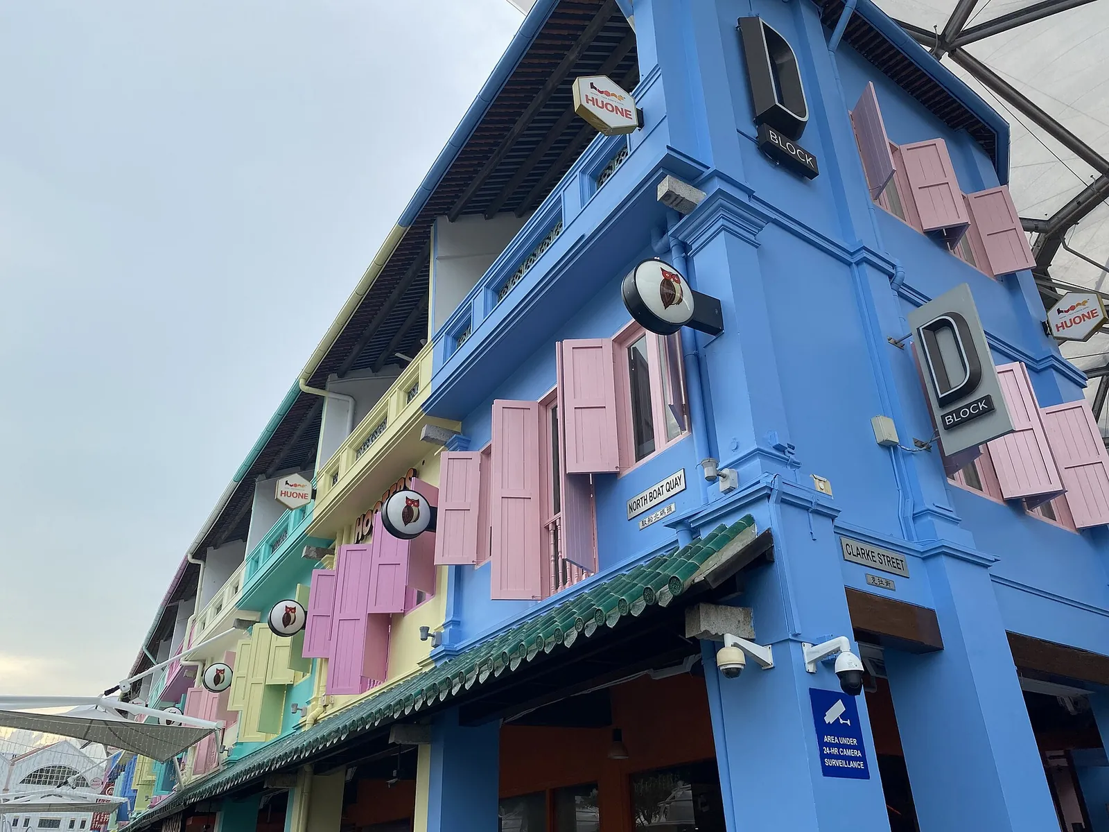 Modrá a pastelová fasáda obchodního domu s ozdobnými okenicemi v Clarke Quay