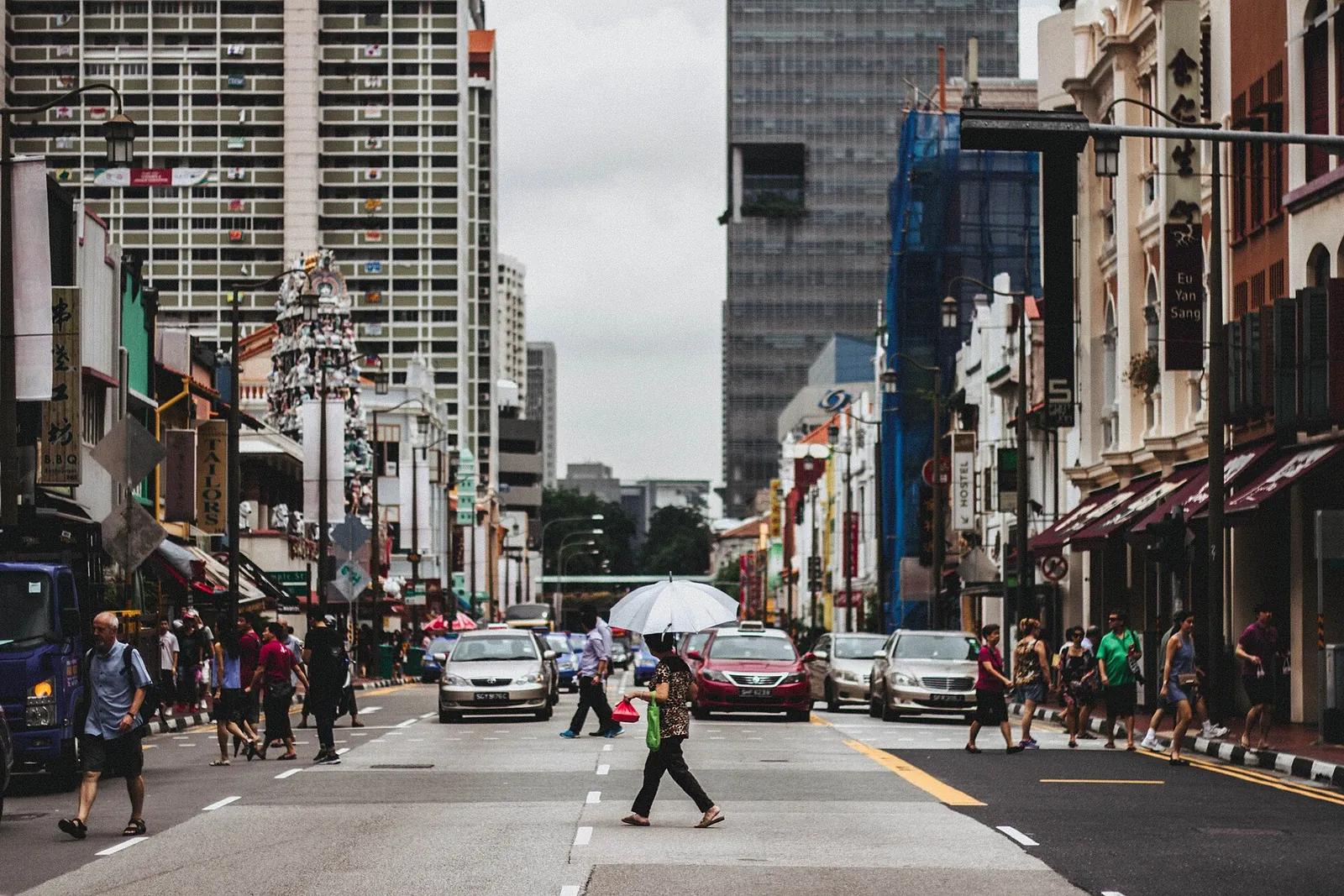 Fußgänger queren eine Straße zwischen zentralen singapurischen Shophouses und Hochhäusern