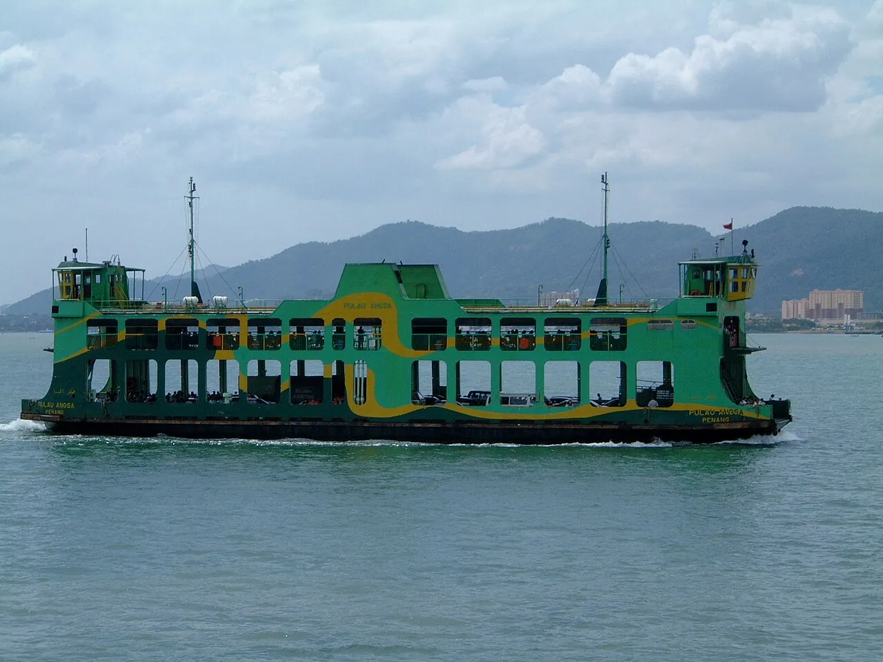 A green-and-yellow Penang ferry crossing from Butterworth toward George Town