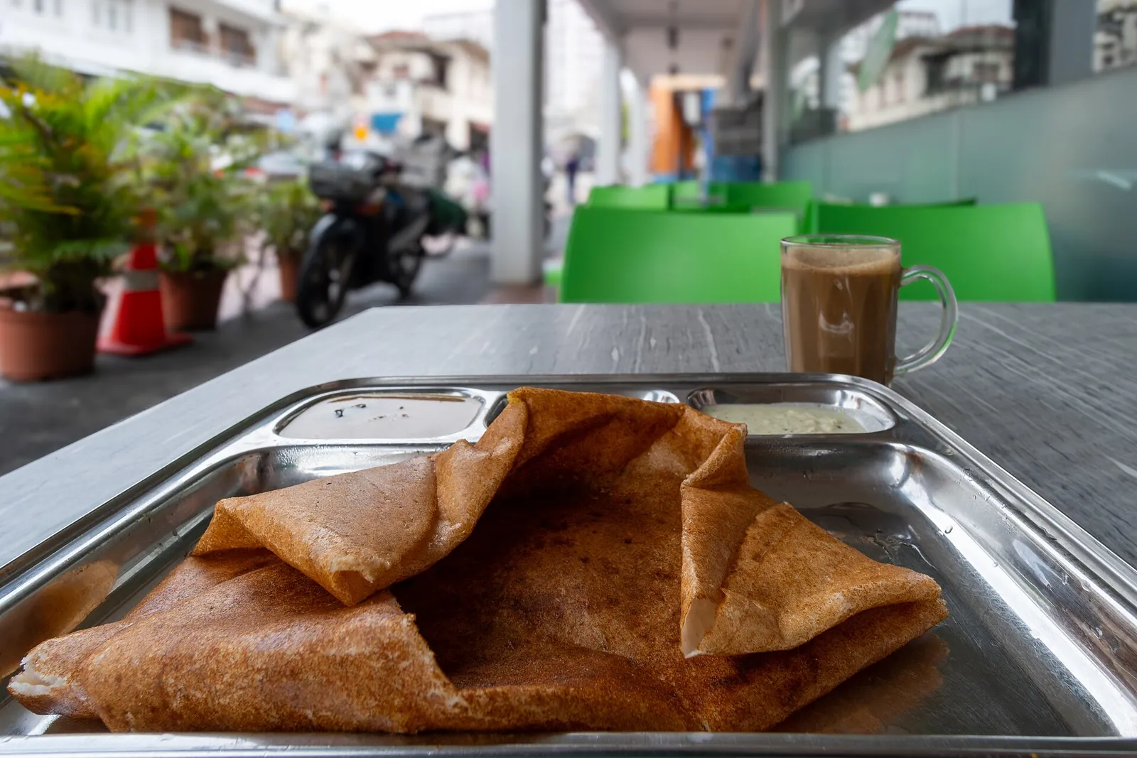 Přeložená dosa na kovovém tácu na venkovním stole v singapurské Little India