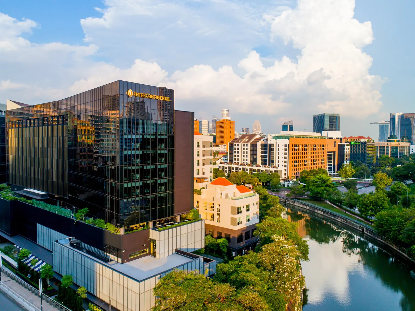 Edificios hoteleros soleados y vegetación junto al río en Robertson Quay, Singapur