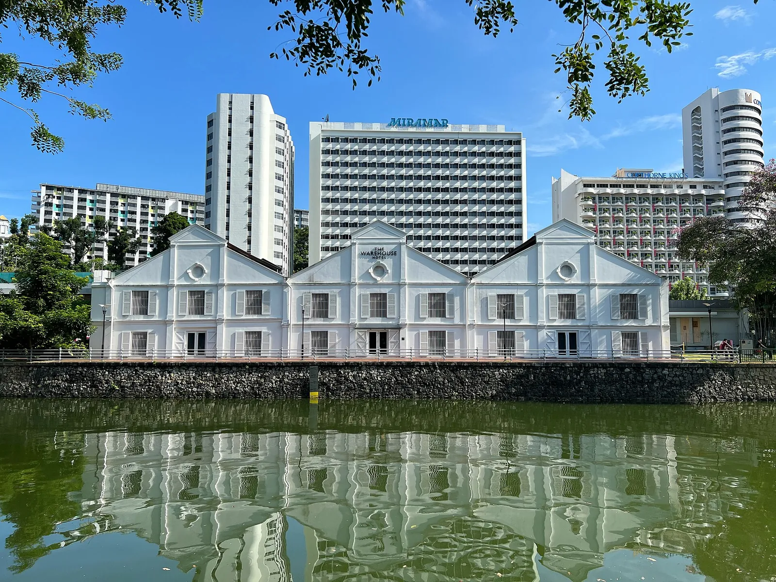 El edificio histórico blanco de Warehouse Hotel reflejado en el río Singapur