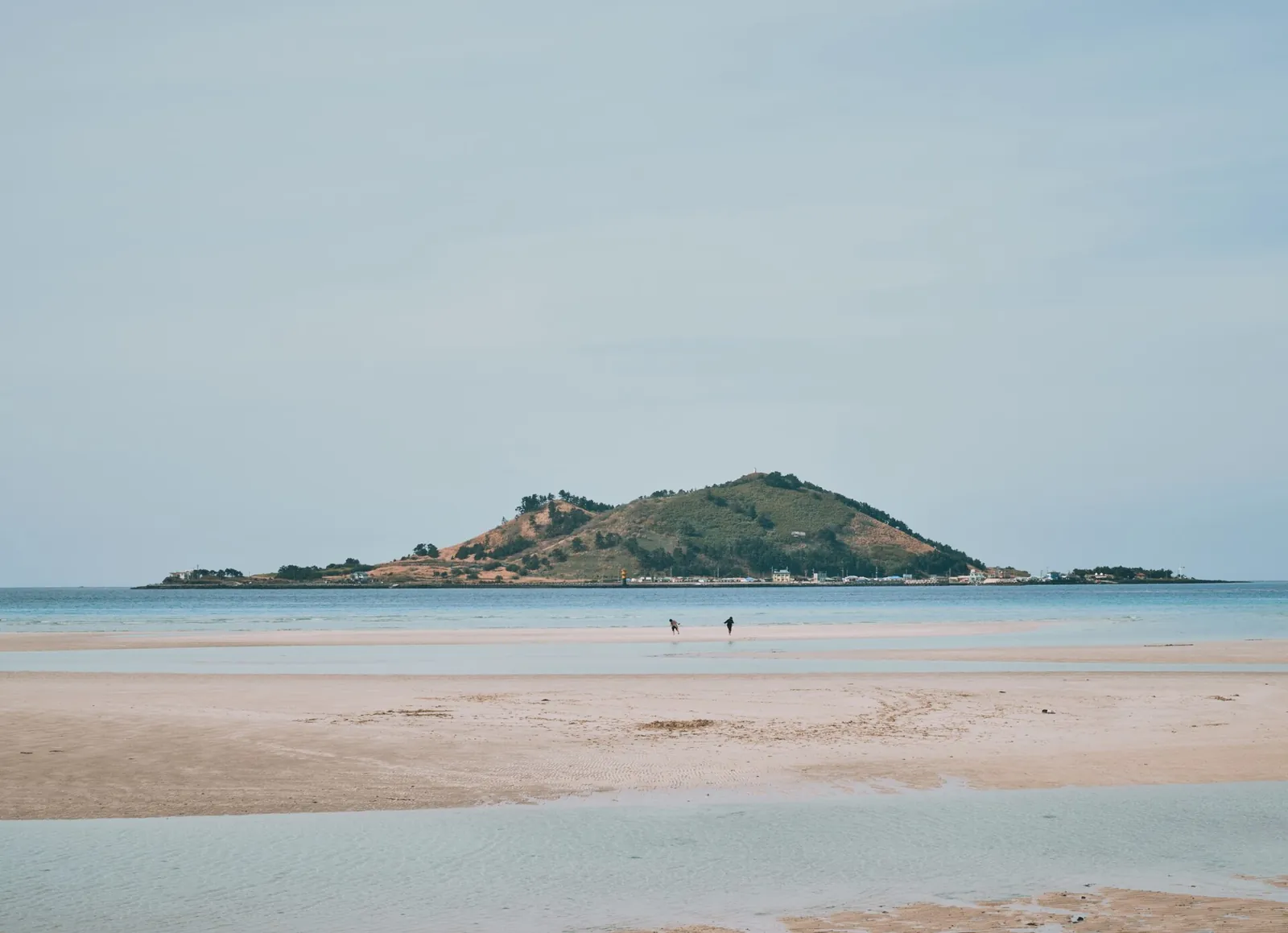 Wide sandy shore at low tide at Geumneung Beach, with Biyangdo Island across the shallow water