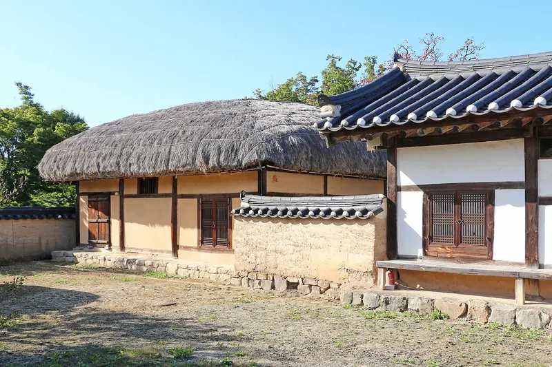 A thatched-roof cottage beside a tile-roofed hanok in Hahoe Folk Village, Andong
