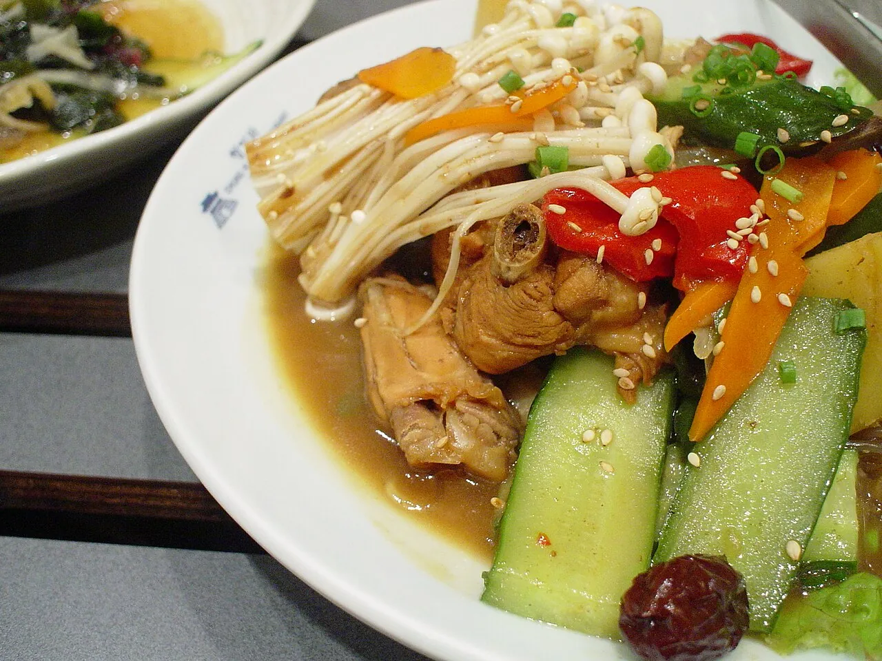 A plate of jjimdak: braised chicken with glass noodles, cucumber, carrot, peppers and enoki mushrooms