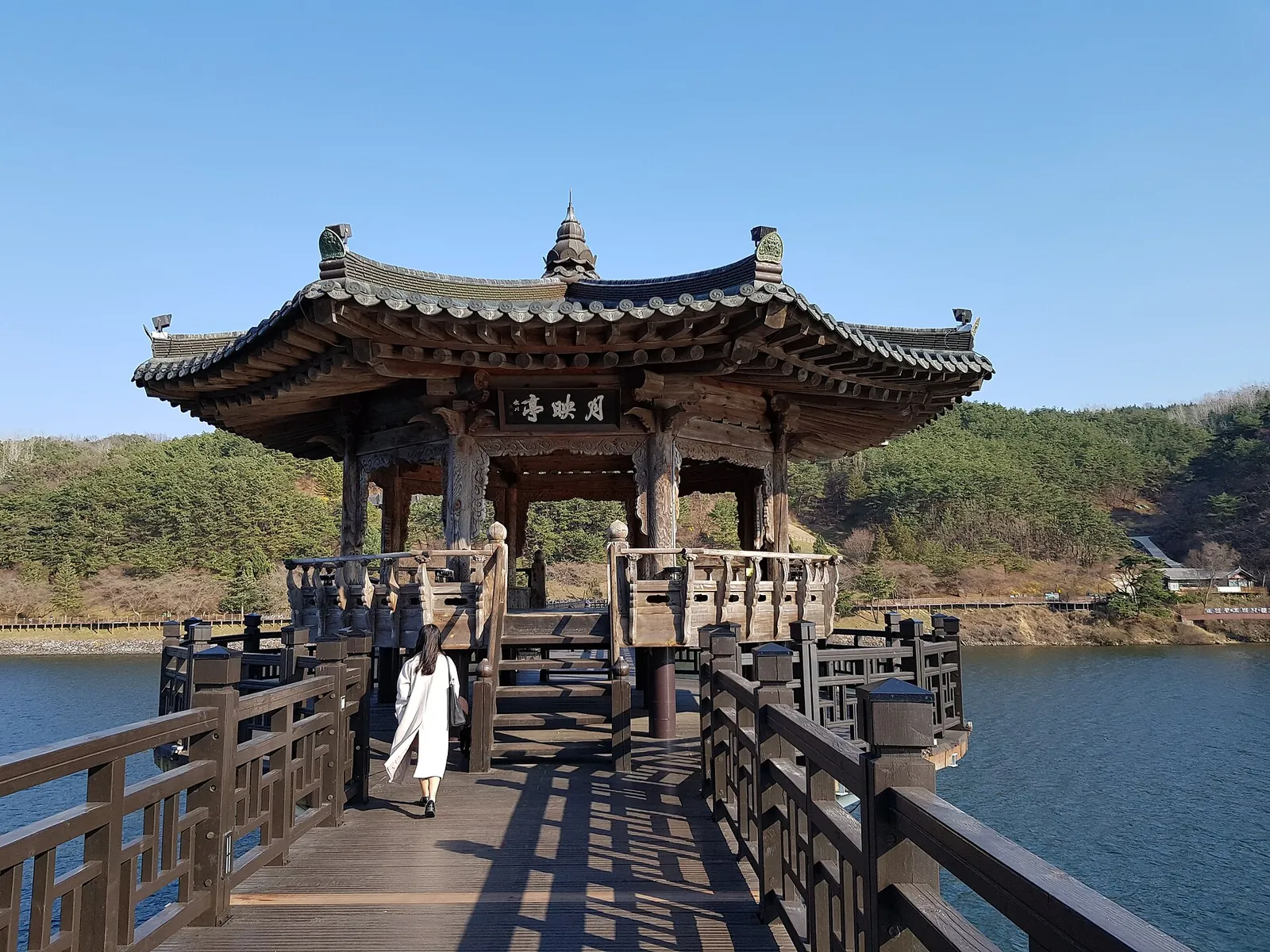A pavilion on Woryeonggyo footbridge over the water with wooded hills behind