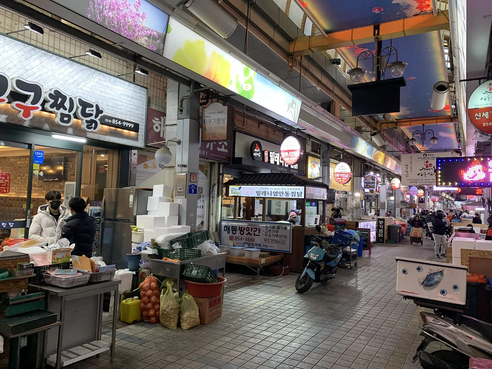 A covered market lane with restaurant signs in the Andong Old Market jjimdak alley