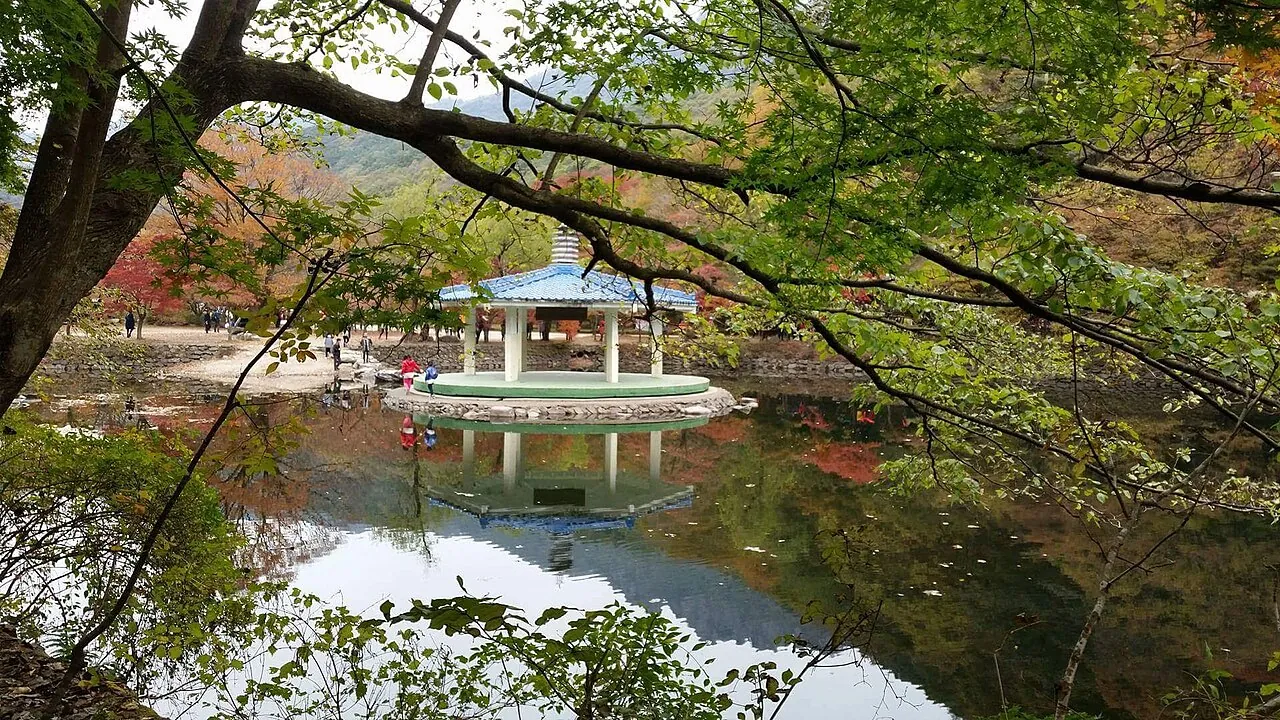 A pavilion by a still lake framed by autumn trees at Naejangsan