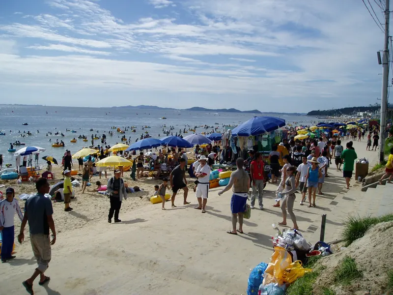 Crowds, beach umbrellas and swimmers on the sand at Daecheon Beach in Boryeong during the Mud Festival