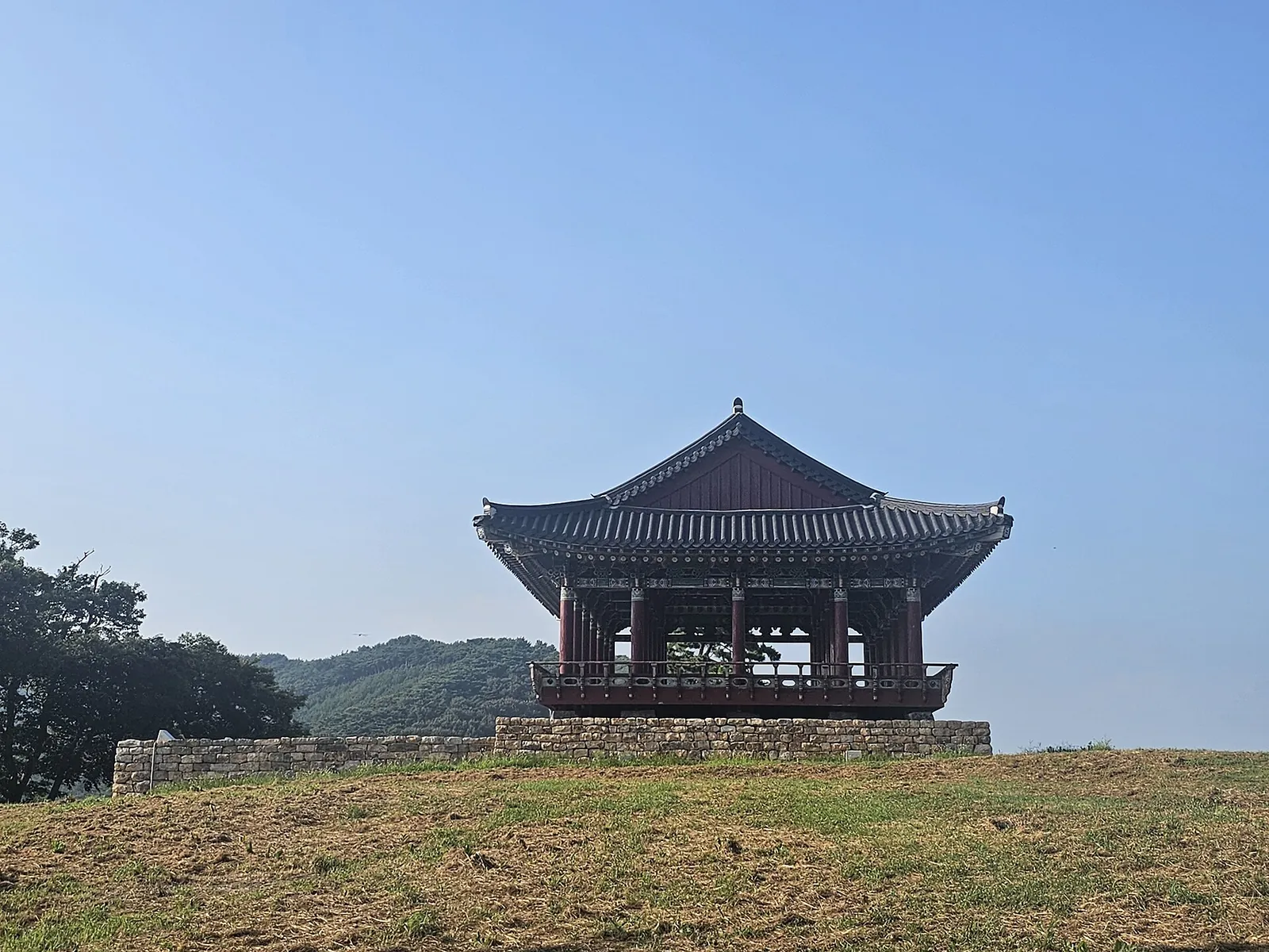 Traditional pavilion with a curved tiled roof on a grassy rise at Chungcheong Suyeongseong in Ocheon, Boryeong