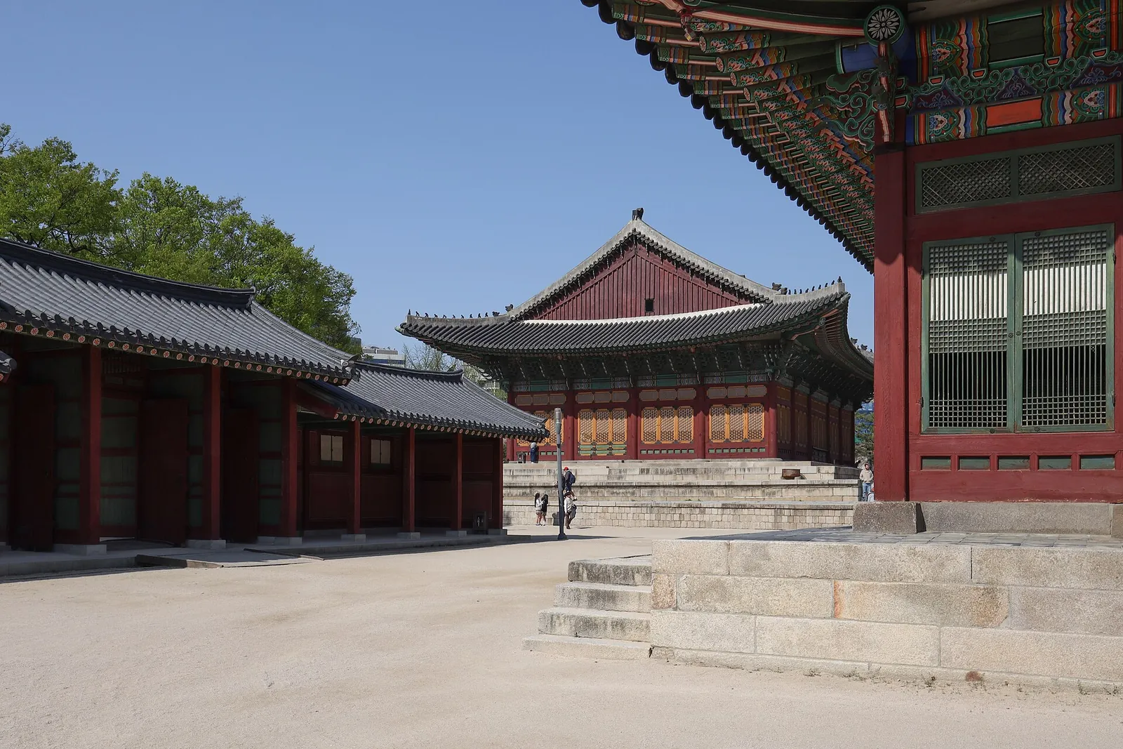 Wooden palace halls with green-painted eaves around a sunny courtyard at Deoksugung Palace in Seoul