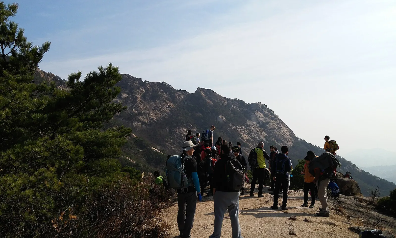 Group of hikers on a rocky viewpoint with granite ridges behind them in Bukhansan National Park