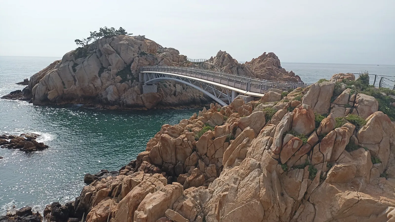 Granite sea rocks of Daewangam Park in Ulsan with the iron footbridge to the rock islet