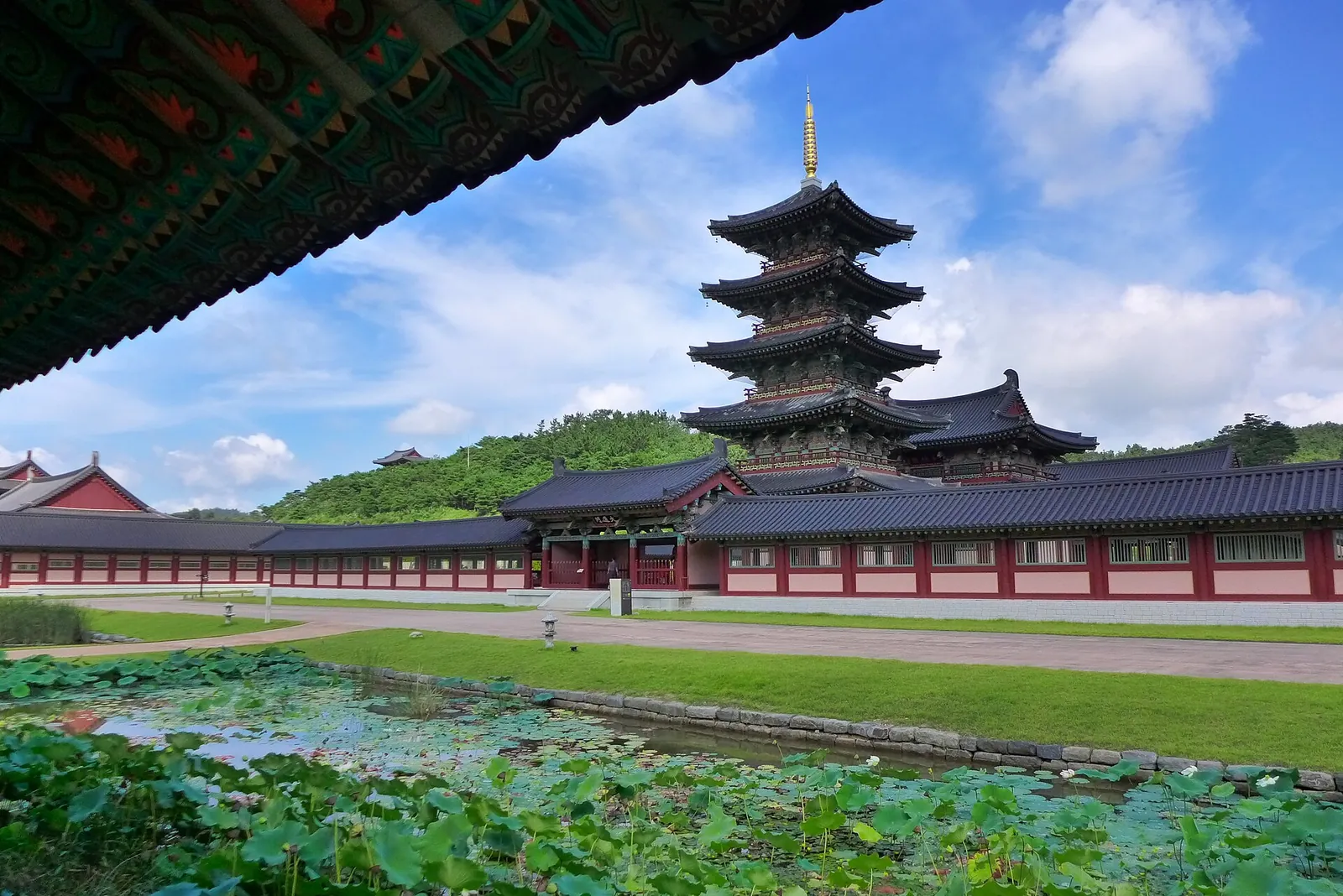 Reconstructed five-storey wooden pagoda and temple halls beyond a lotus pond at Baekje Cultural Land in Buyeo