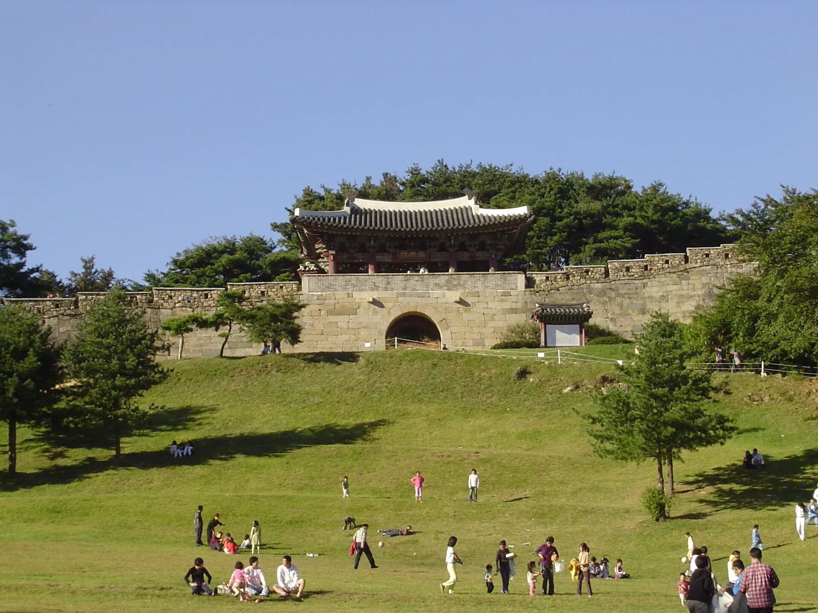 Gongnammun, the south gate of Sangdangsanseong Fortress in Cheongju, with its gate tower above a grassy slope and visitors on the lawn