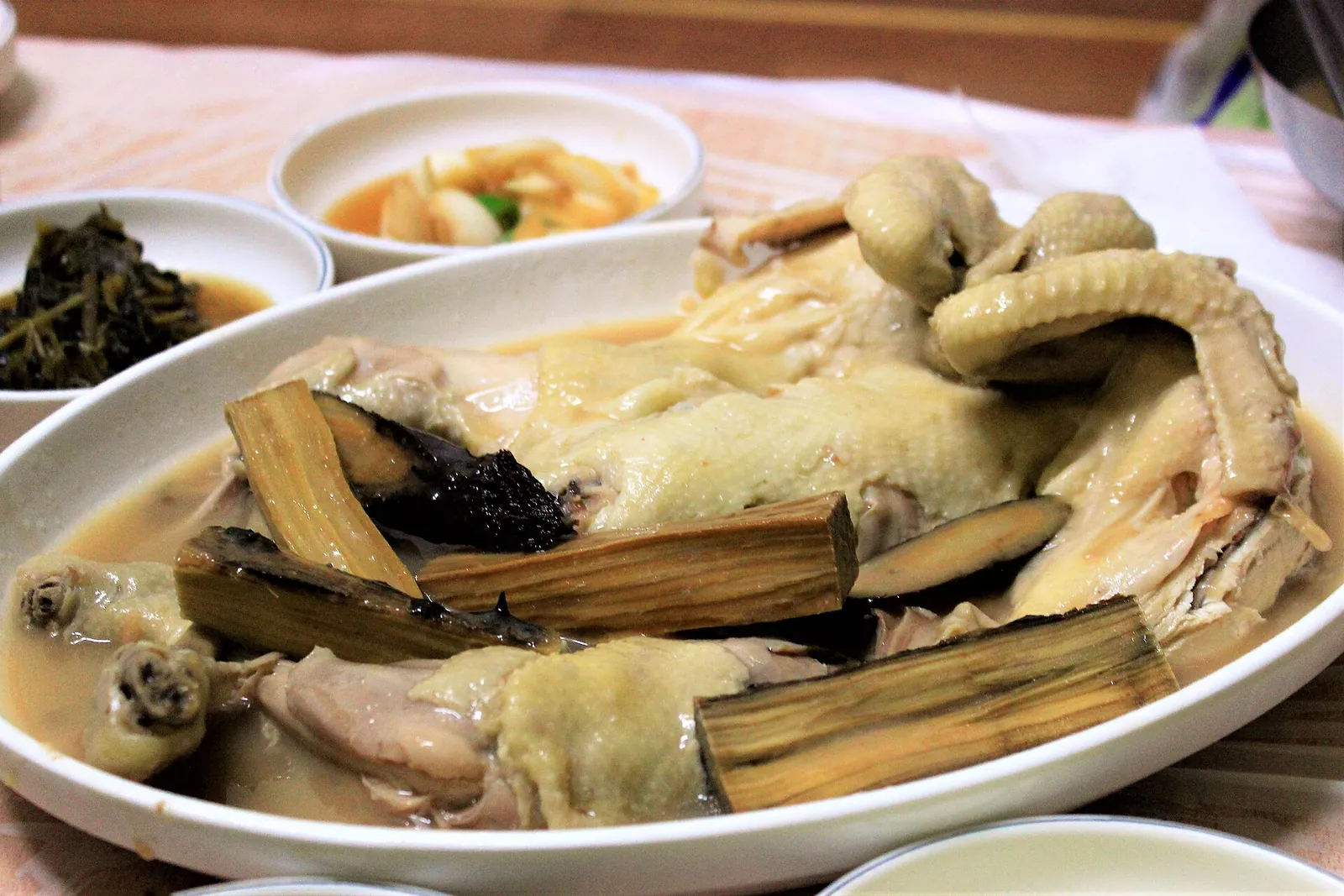 A whole boiled chicken with medicinal herbs on a platter, with side dishes, at Dalgi Mineral Spring