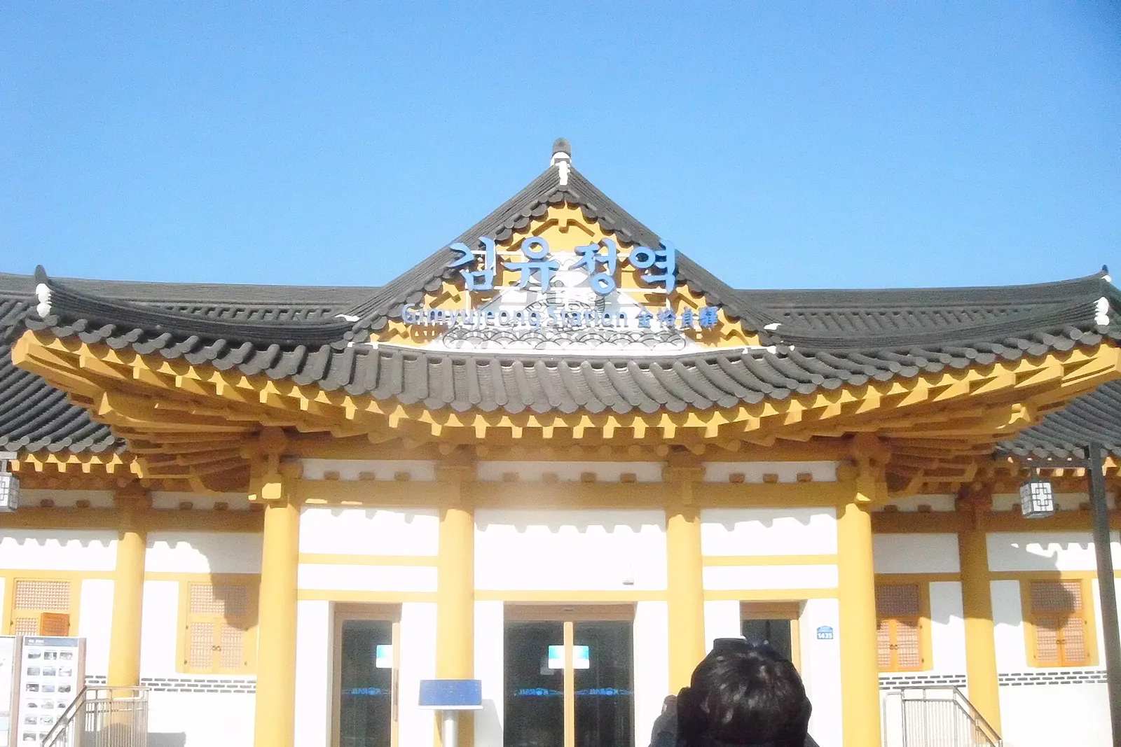 Hanok-style building of Gimyujeong Station with a curved tiled roof under a blue sky