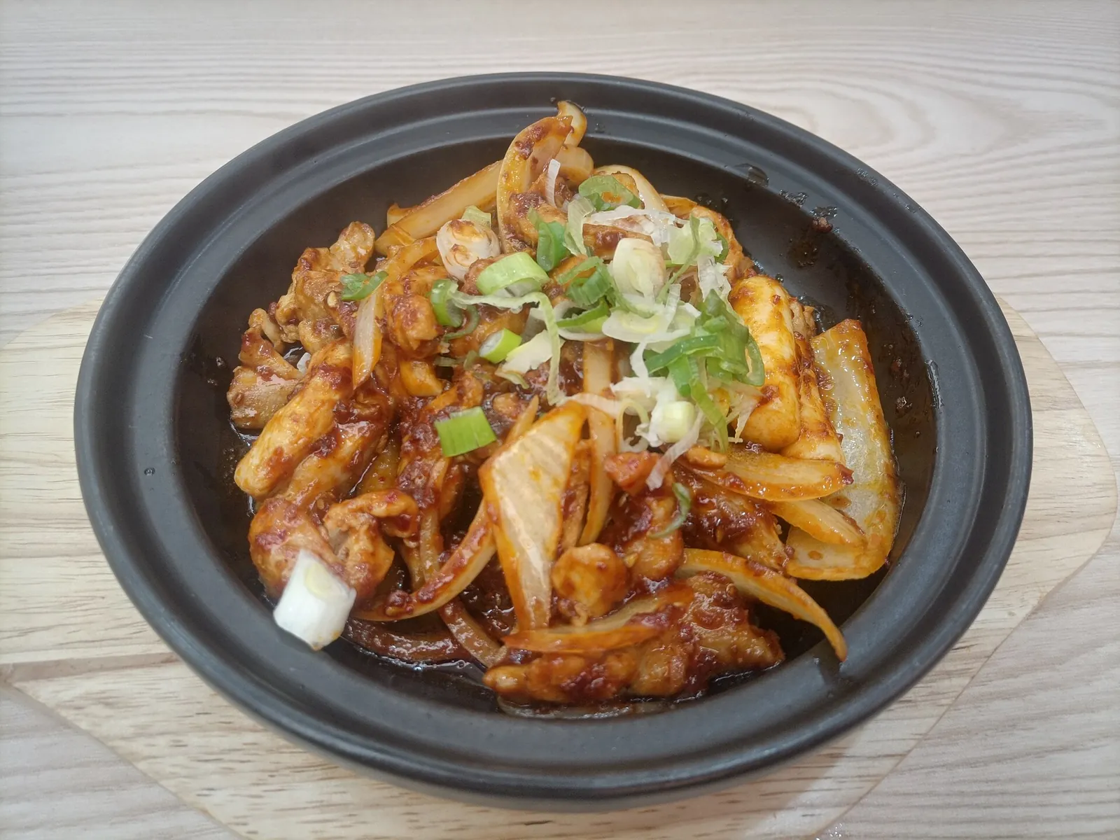 Chuncheon-style dakgalbi: spicy stir-fried chicken with cabbage and spring onion in a black dish