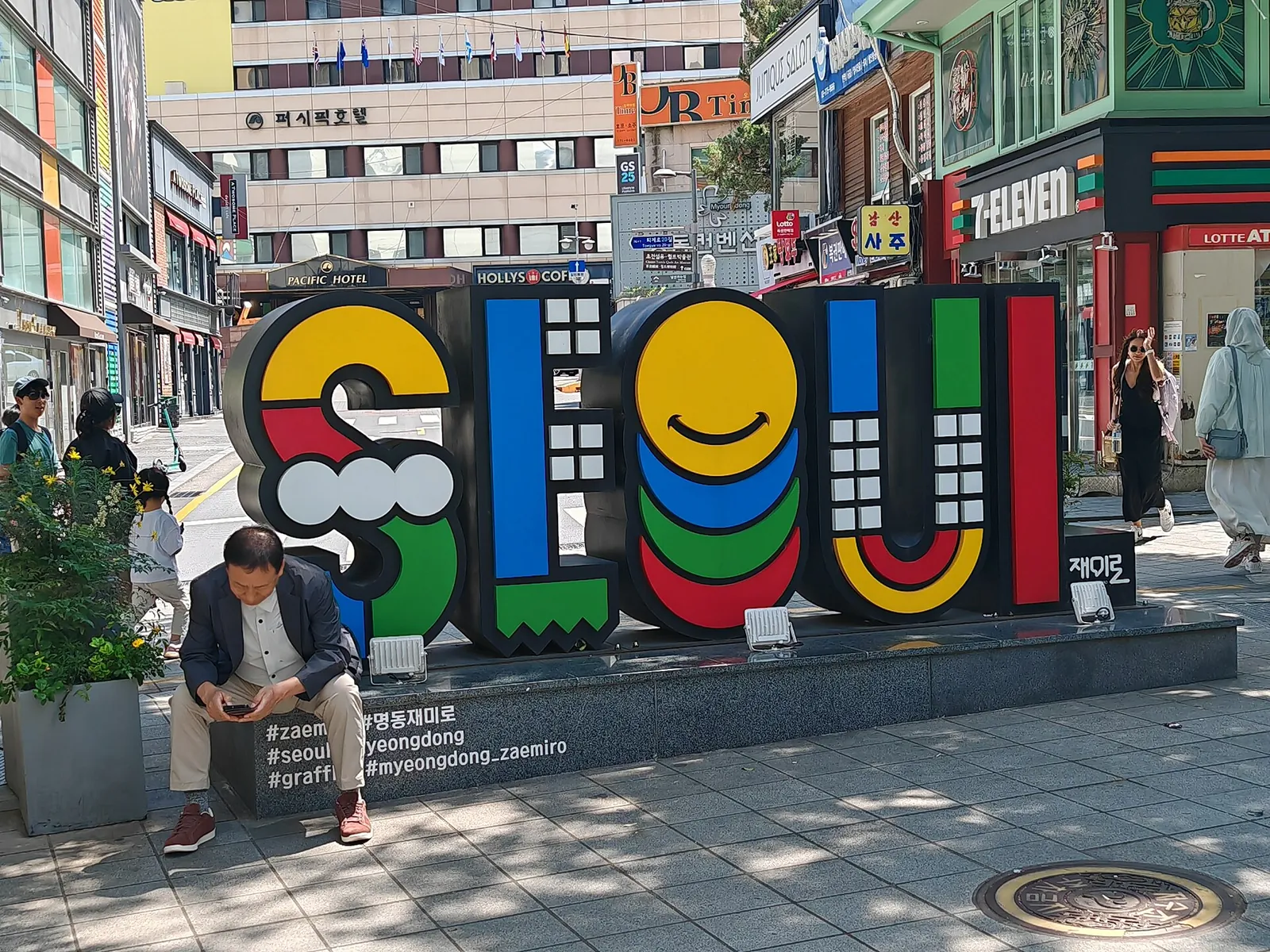 Colourful Seoul city sign on a pedestrian street in Myeongdong, Seoul, with shops and a 7-Eleven behind it