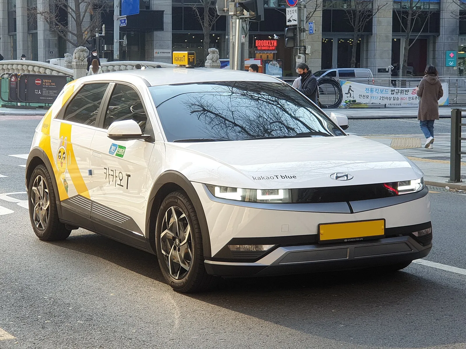 White and yellow Hyundai Ioniq 5 taxi with Kakao T branding on a city street in South Korea