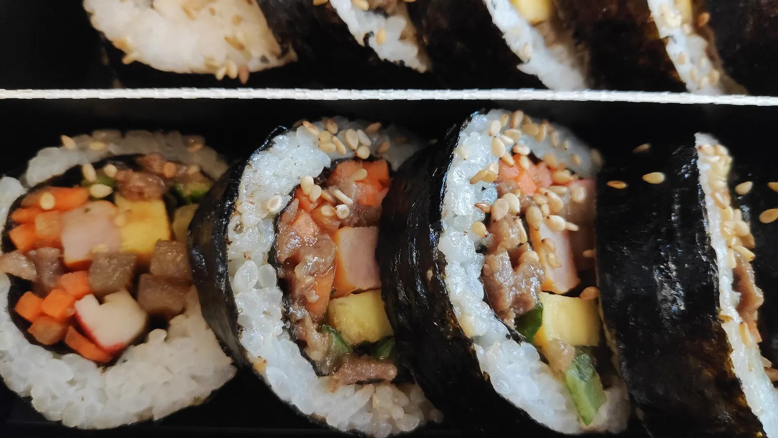 Close-up of sliced gimbap rolls with rice, egg and vegetables in seaweed, bought for a KTX train journey