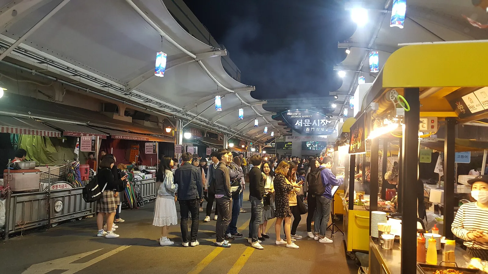 Crowds queueing at lit food stalls under the canopies of Seomun Night Market in Daegu after dark