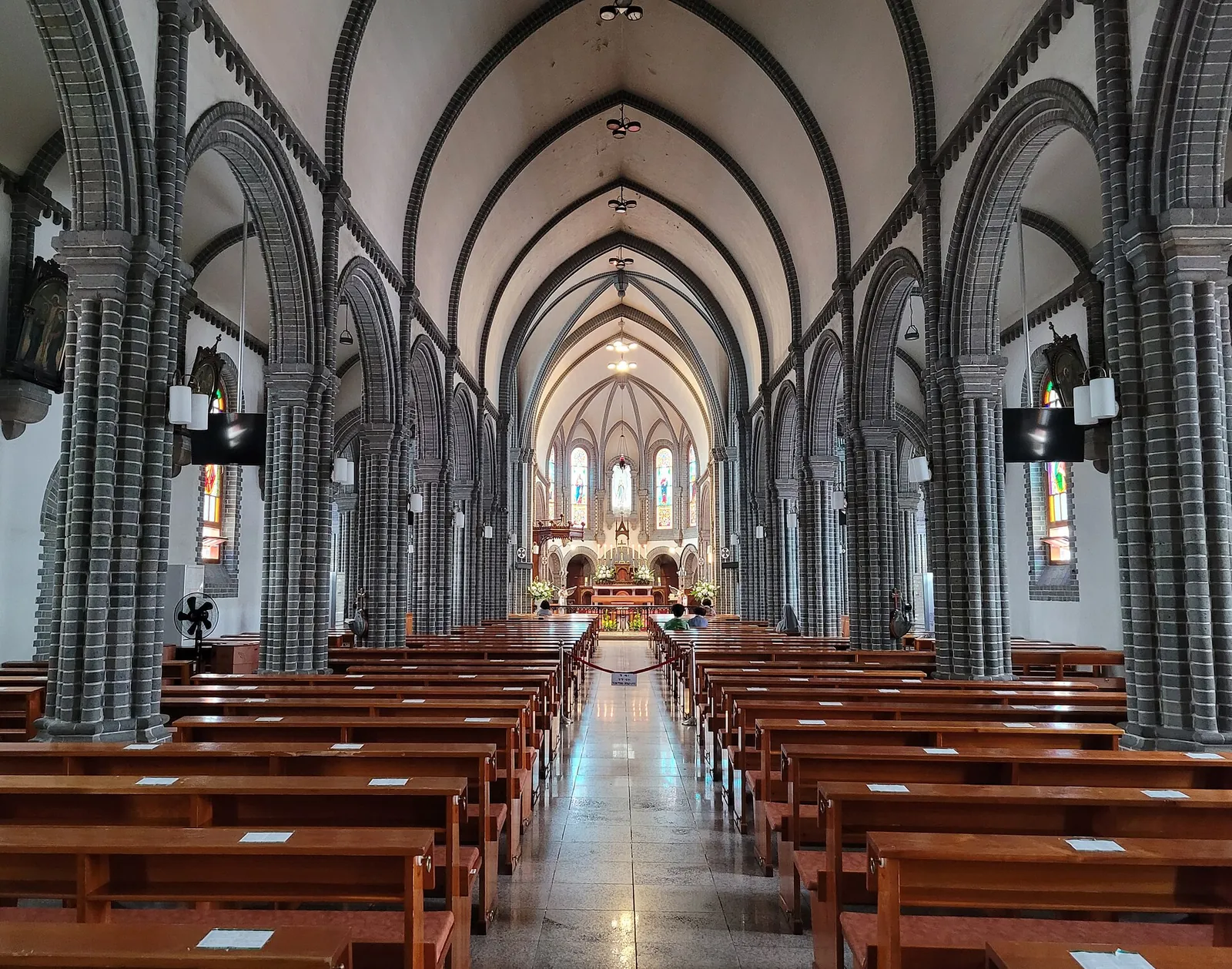 The nave of Gyesan Cathedral in Daegu, with rows of wooden pews, pointed arches and the altar at the far end