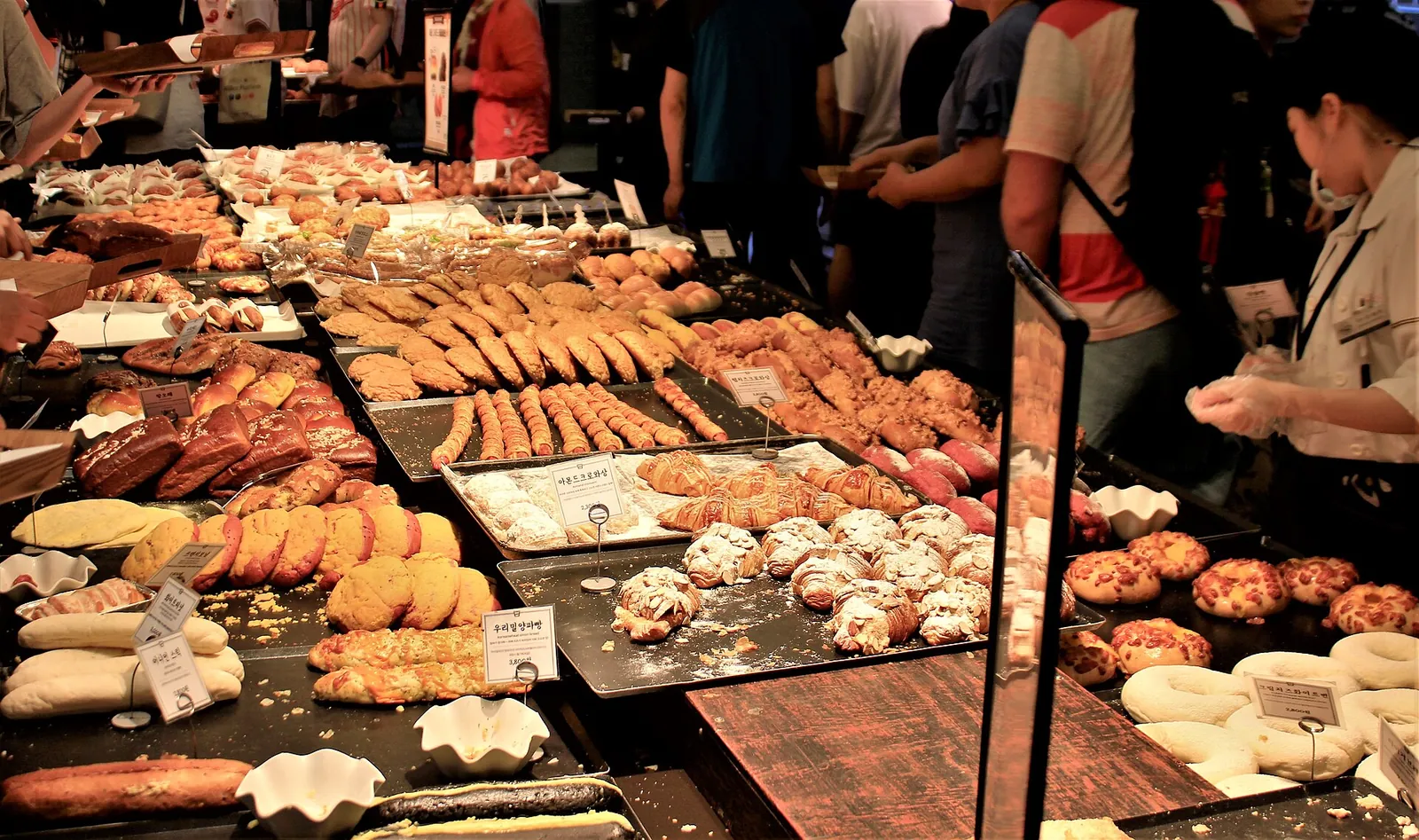 Trays of breads and pastries on the display counter at Sungsimdang bakery in Daejeon, with customers choosing
