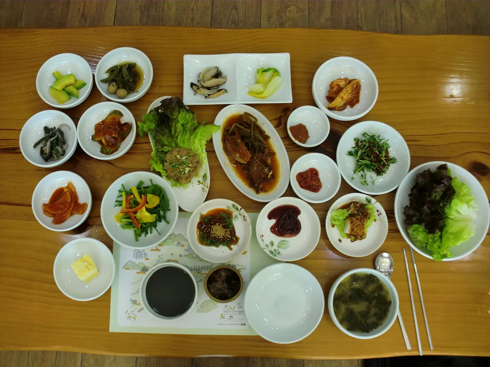 A daetongbap set meal on a wooden table with a dozen small side dishes, eaten in Damyang