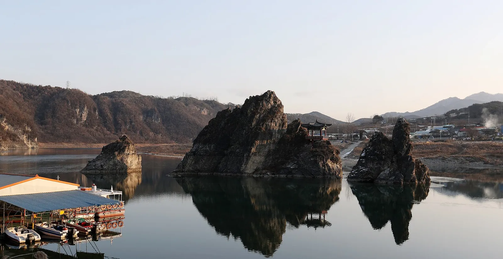 The three limestone peaks of Dodamsambong reflected in the still Namhangang River at Danyang, with Samdojeong Pavilion on the tallest peak